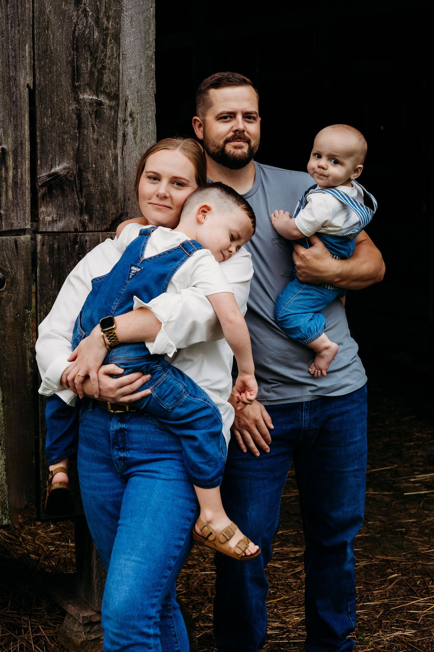 Family shares warm embrace outdoors in a snowy winter field during golden hour sunset.
