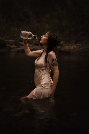 Woman pouring water onto self, seductive, boudoir