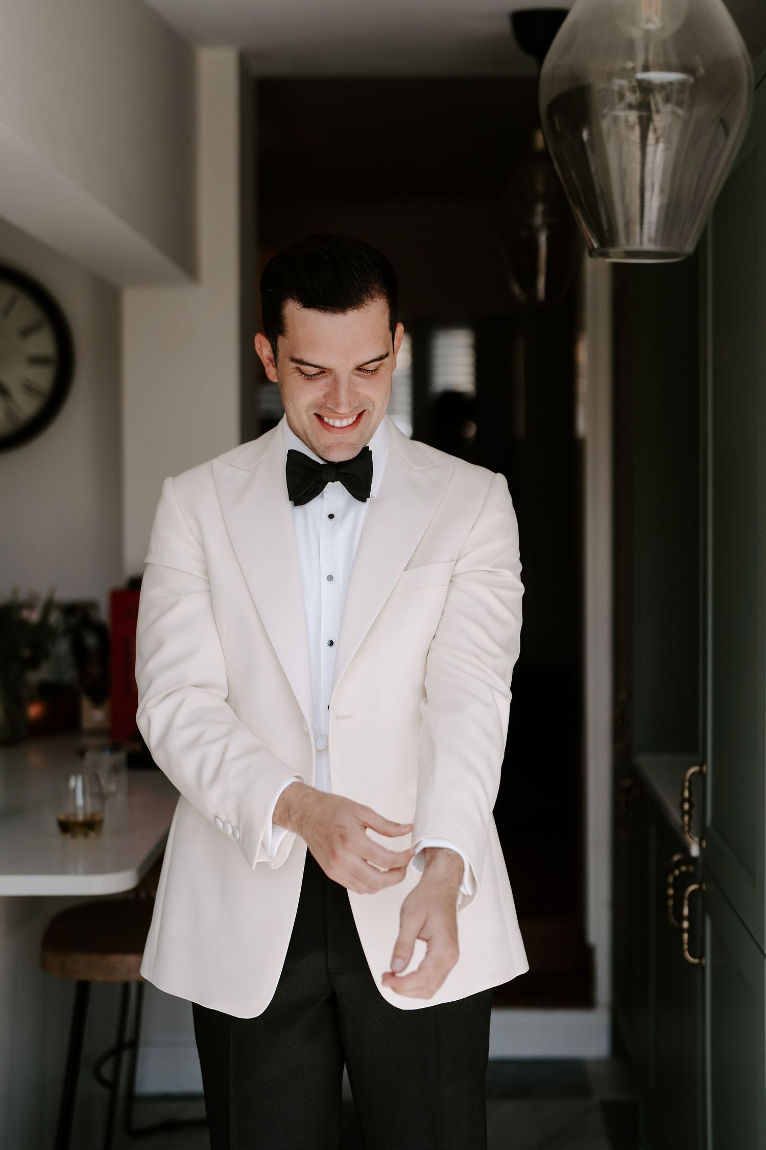 groom adjusting suit jacket and smiling while getting ready at hamswell house in bath