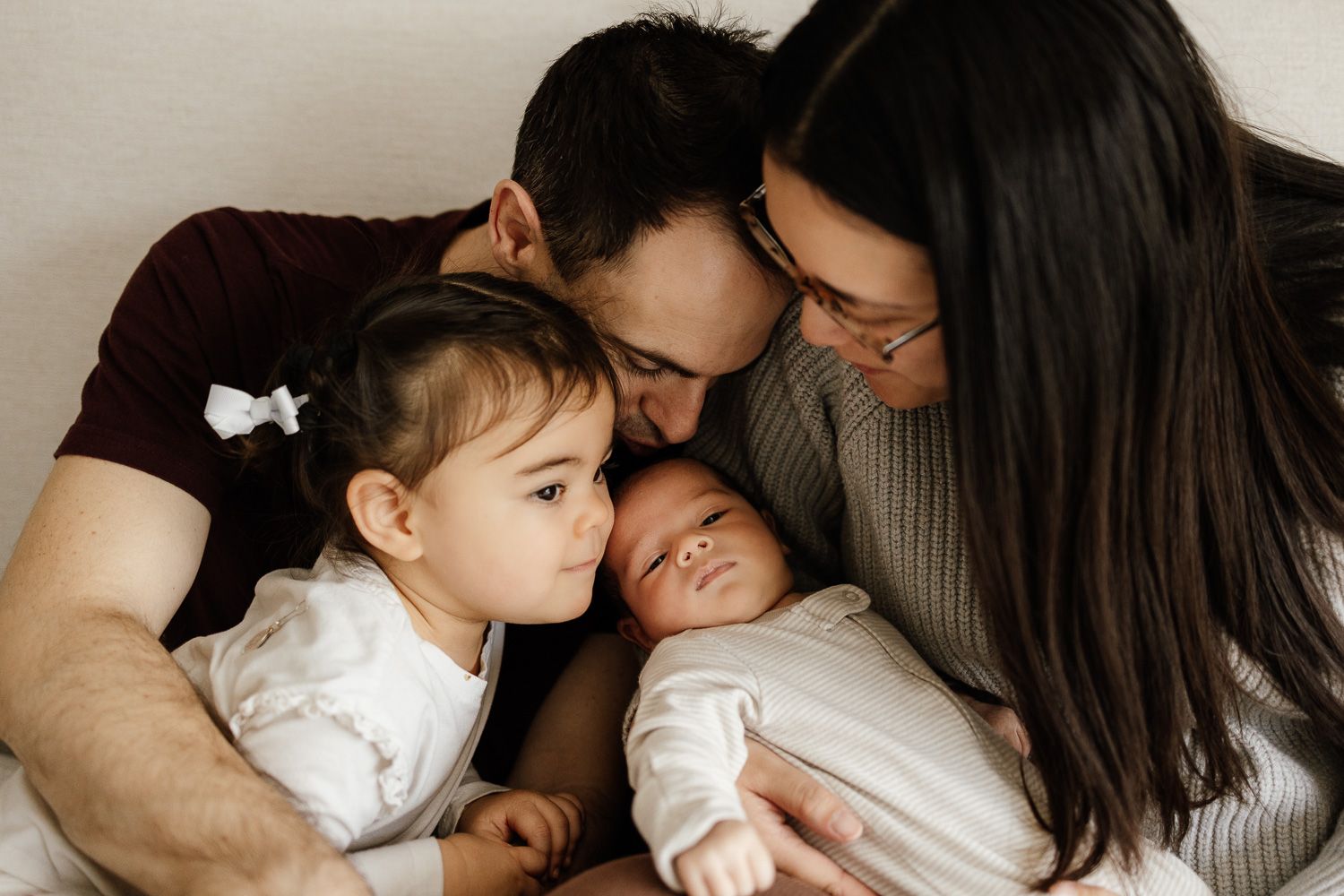 Family kisses their newborn baby boy at their in-home lifestyle baby photoshoot
