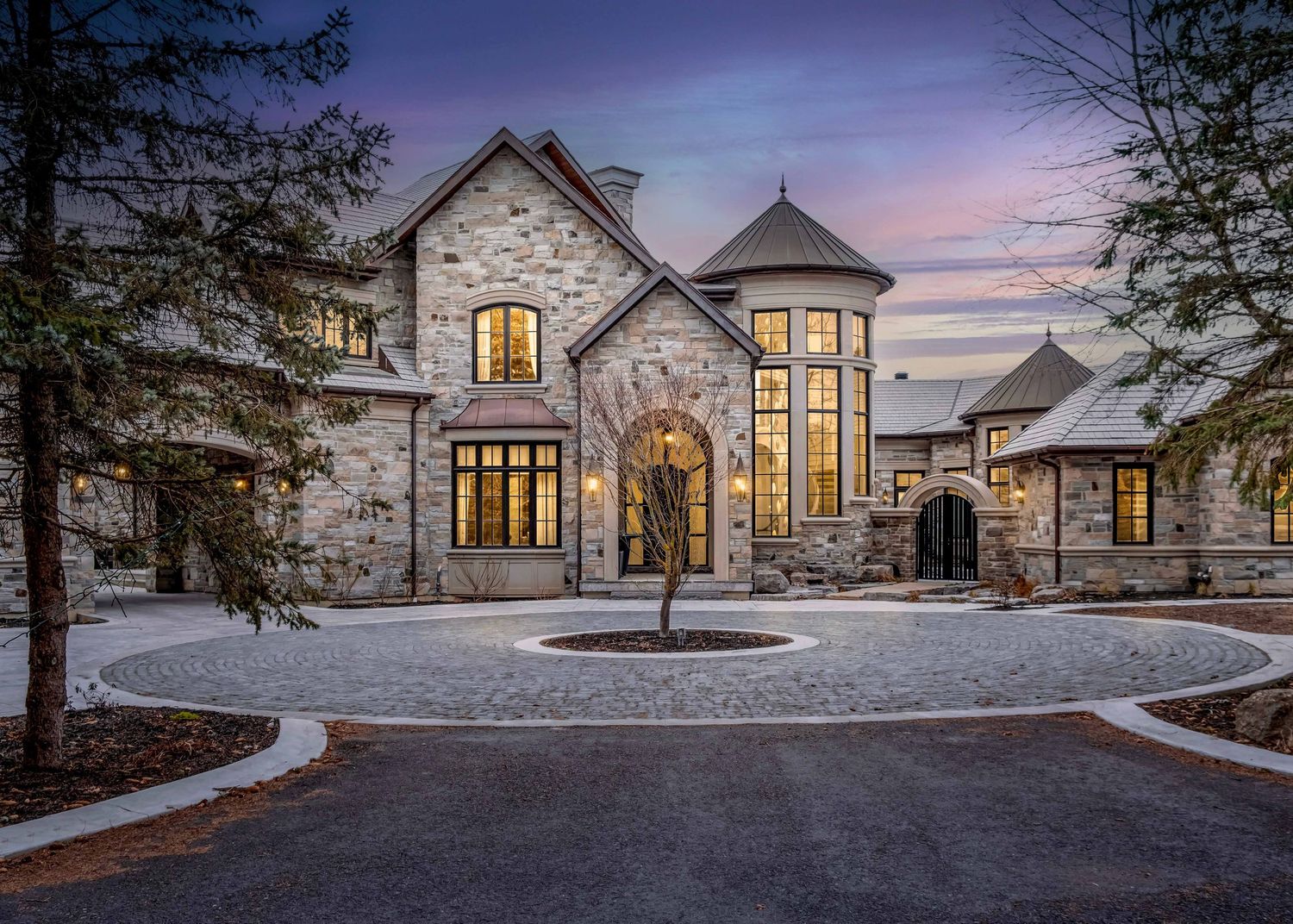 Modern luxury home exterior with warm glowing windows at dusk in winter setting located in King City, ON built by Belairbuild.