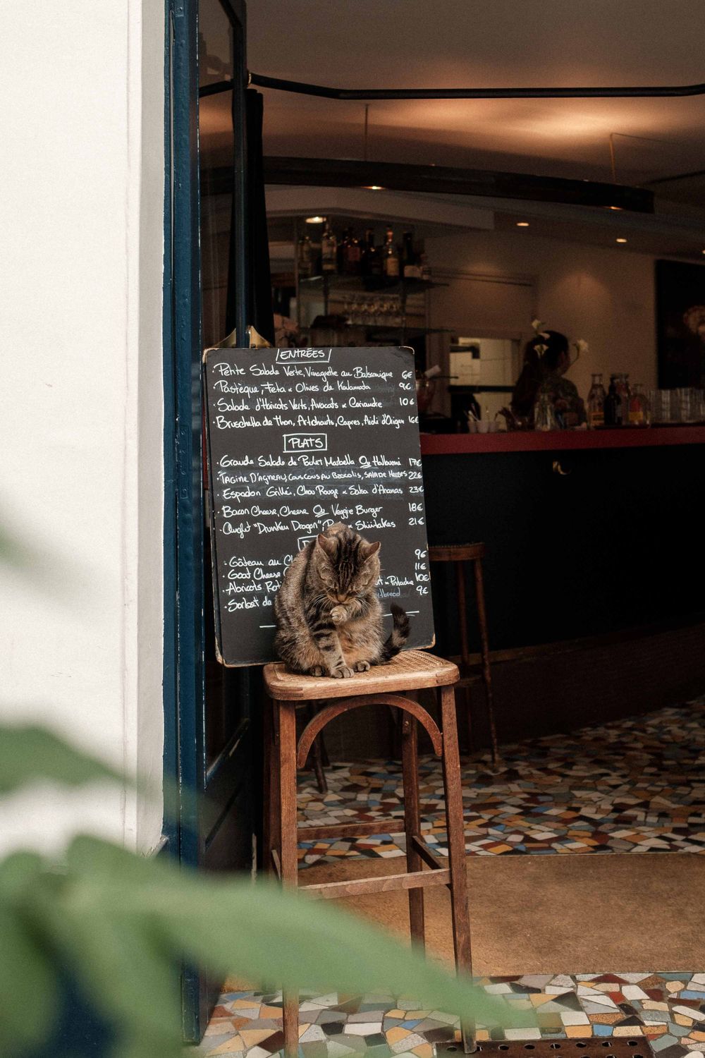 Chalkboard menu and rustic wooden chair against mosaic floor pattern.