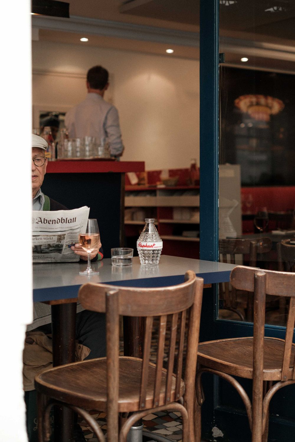 Casual cafe interior with wooden chairs and newspaper on table.