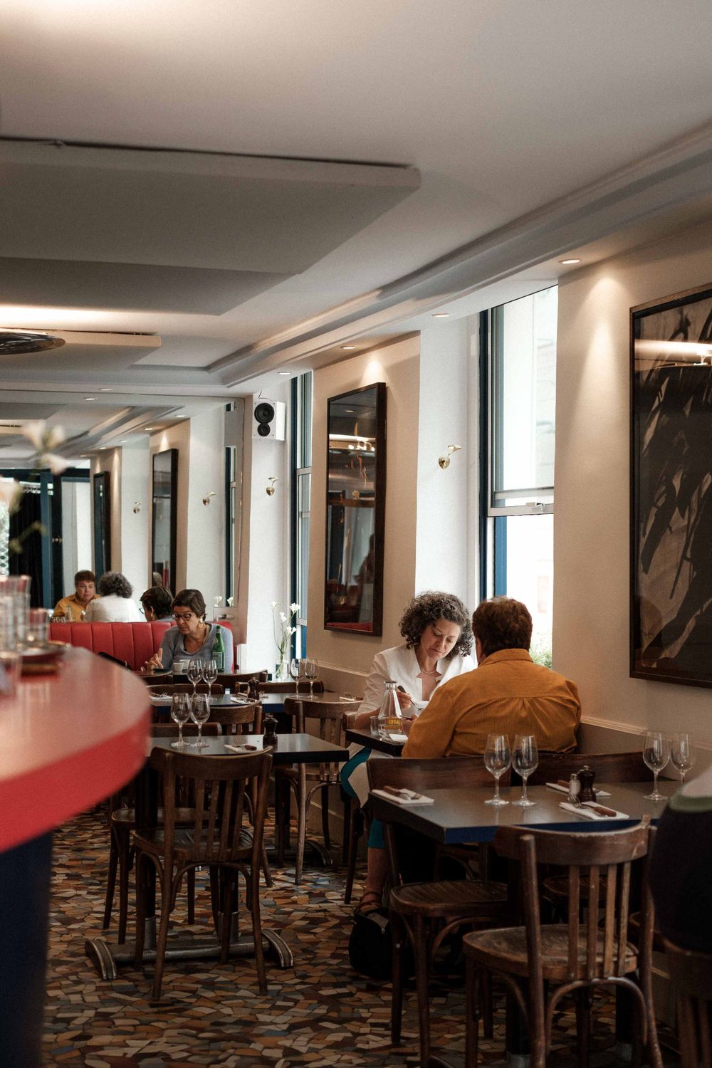 Interior of cozy restaurant with wooden chairs and tables in warm lighting.