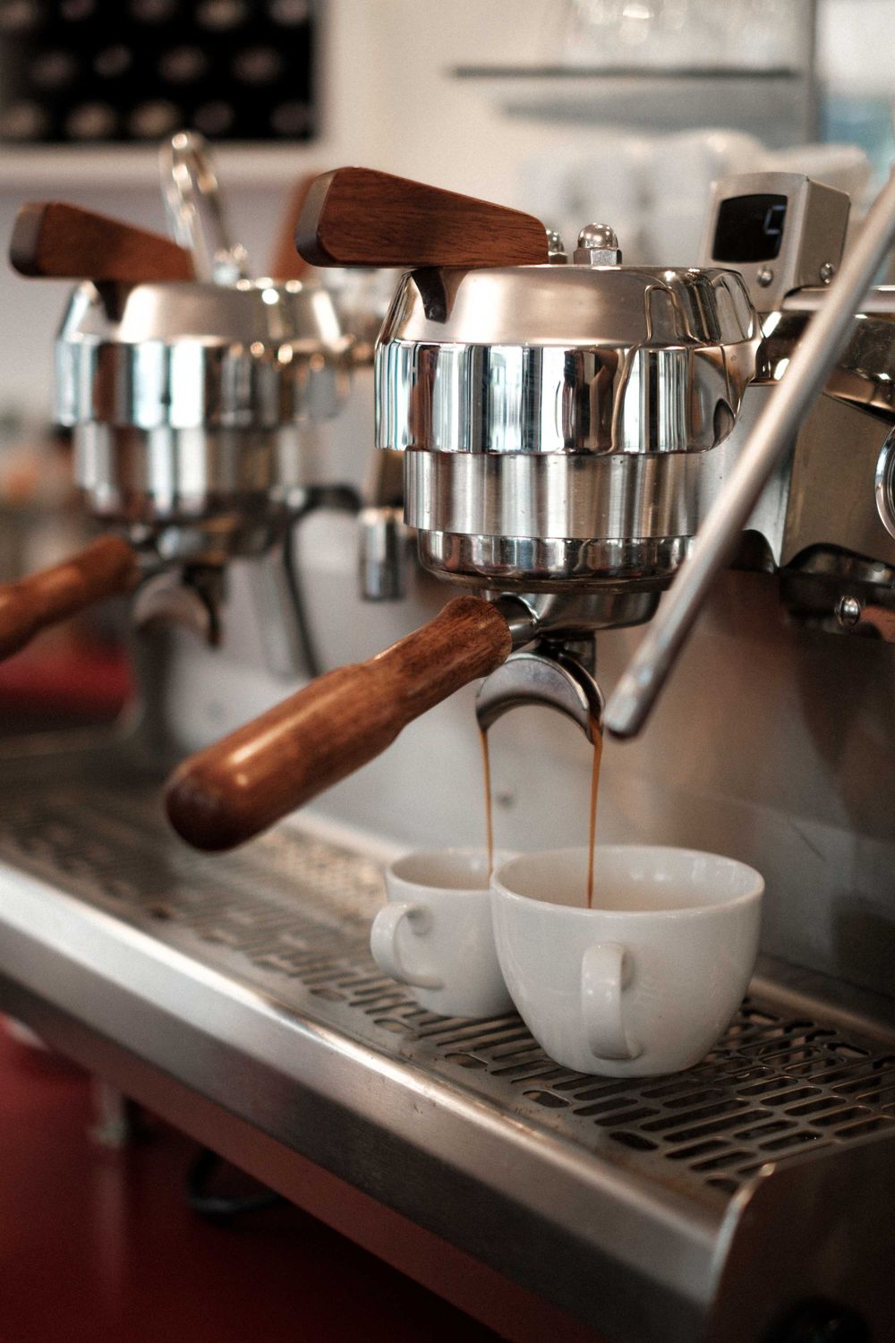 Coffee drips from an espresso machine portafilter into a white ceramic cup.