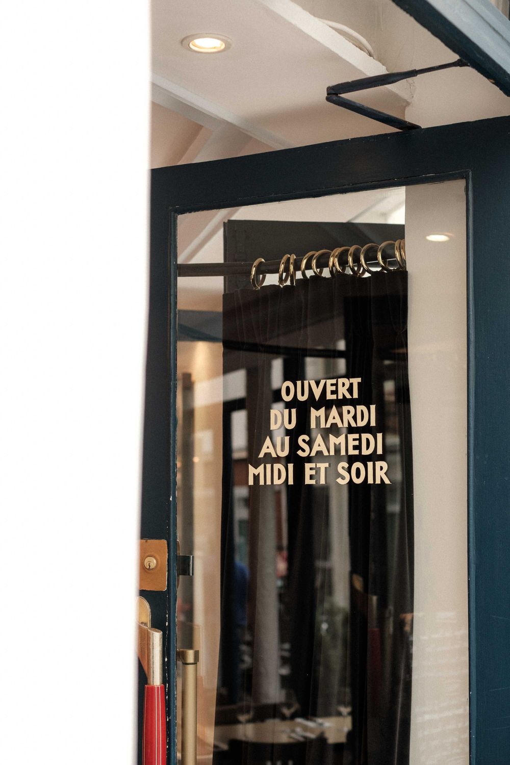 French text on a glass door indicating business hours for a restaurant or shop.