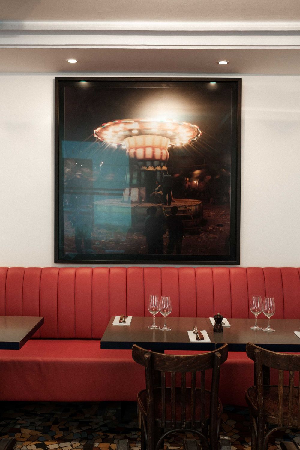 Modern restaurant interior with red banquette seating and illuminated artwork on the wall.