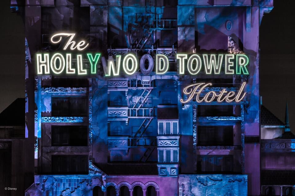 Illuminated Hollywood Tower Hotel sign at night with purple lighting effects.