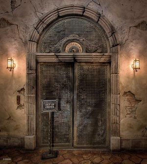 A series of dimly lit stone archways in an underground tunnel or basement corridor with metal gates and service signs.