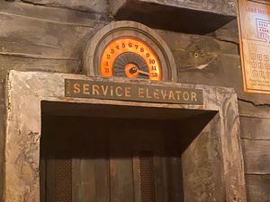An illuminated service elevator entrance with ornate architectural details in a vintage industrial setting.