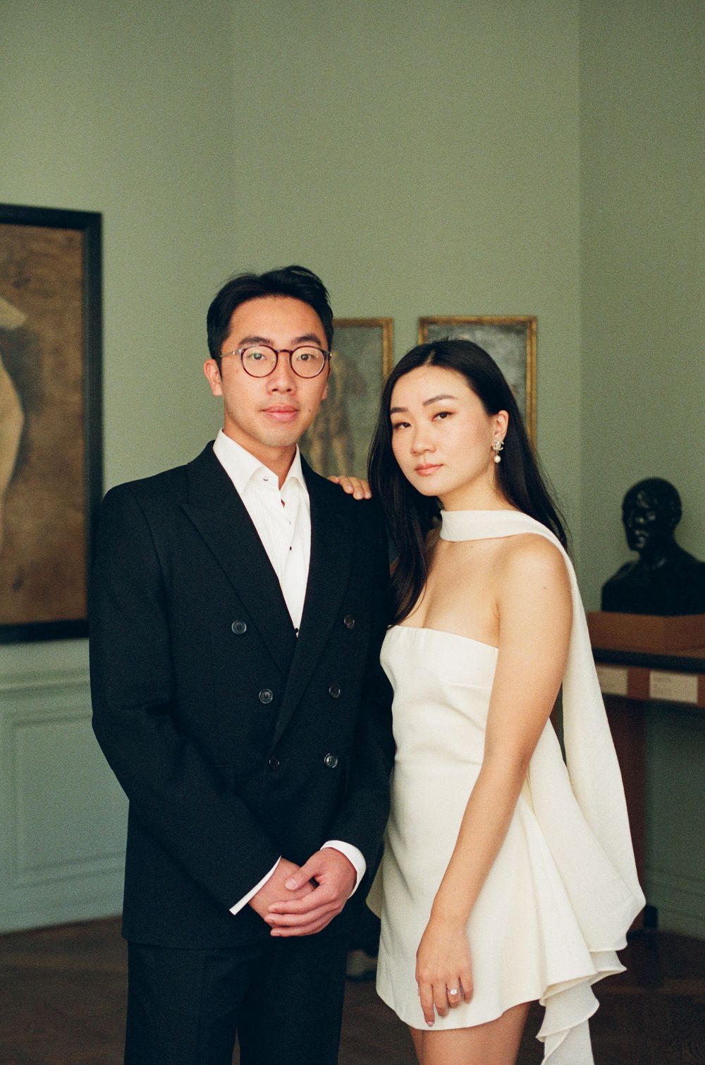 Elegant couple posing in art gallery, man in black suit and woman in white mini dress. musee rodin photoshoot. paris film photoshoot