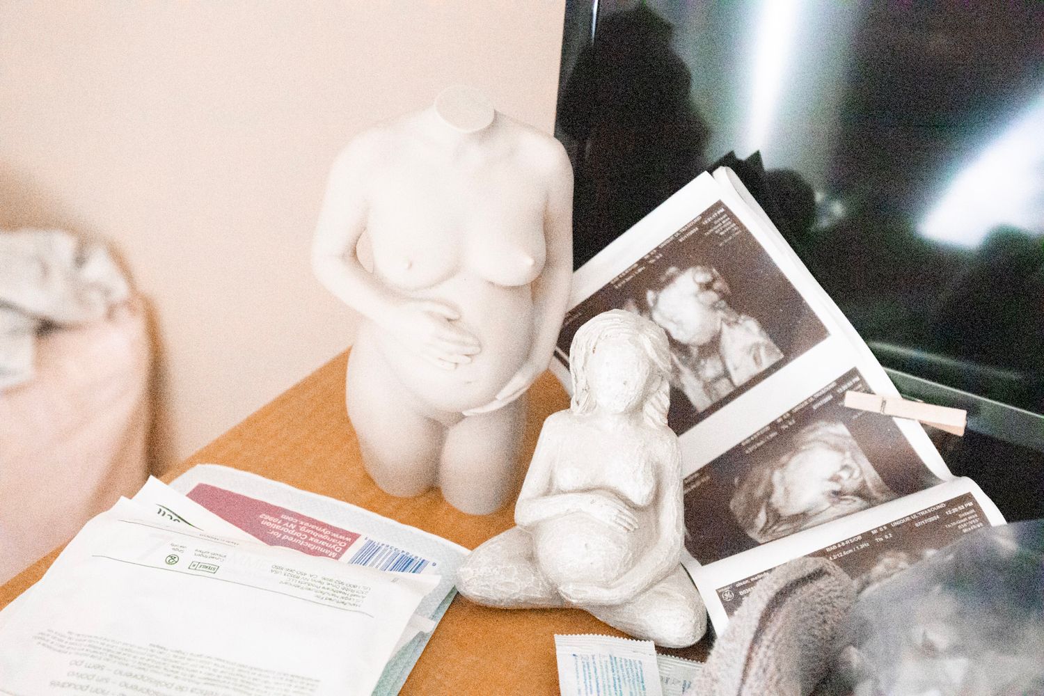 Ultrasound photos displayed next to small white decorative figurines on a wooden surface.
