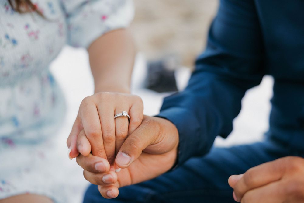 Close-up view of two hands clasped together with a gold wedding ring visible.