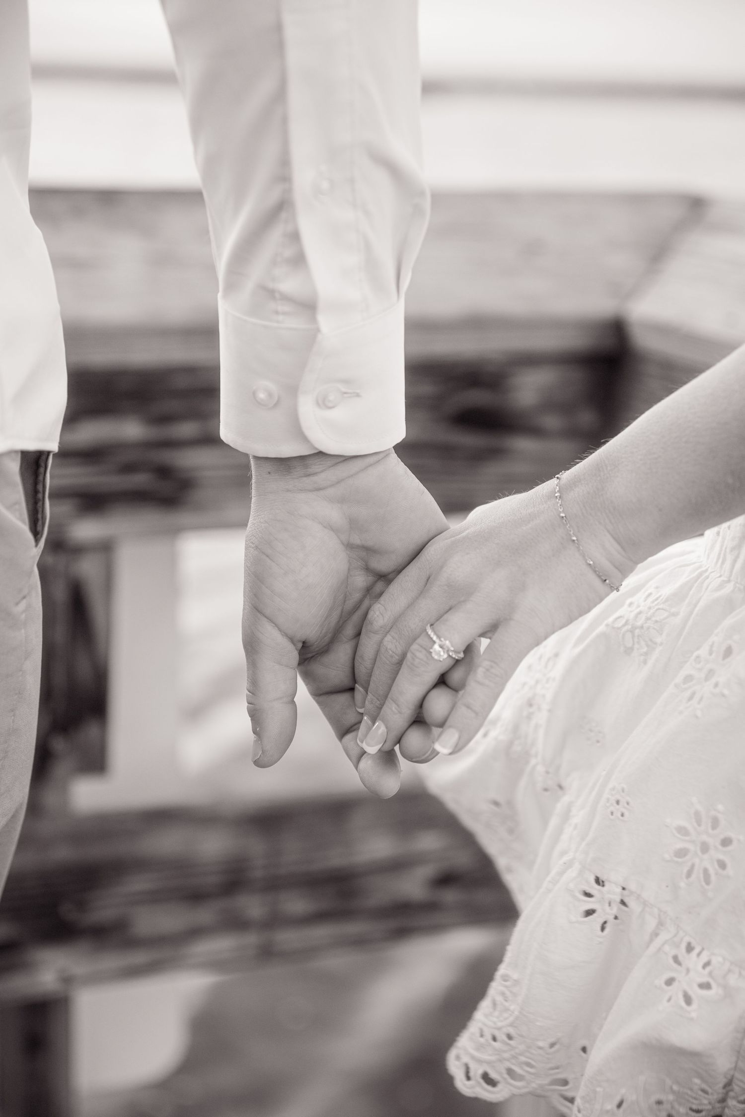 Close-up of hands holding delicate white eyelet lace fabric against a dark background.