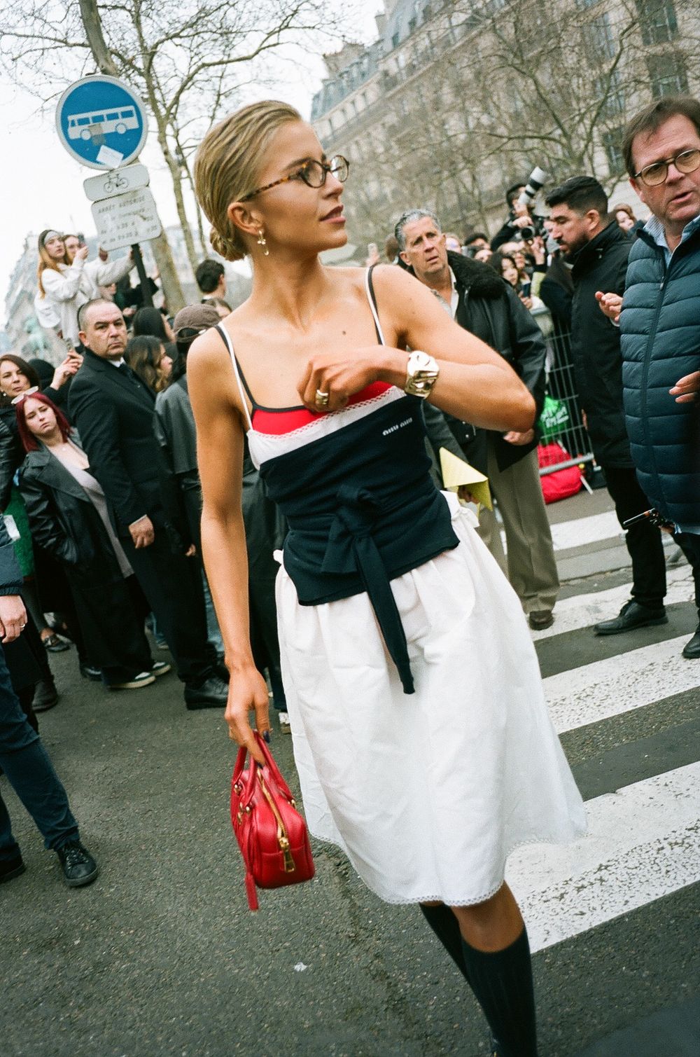 A fashionable street style look featuring a black and white dress with knee socks and a red handbag during Paris Fashion Week.