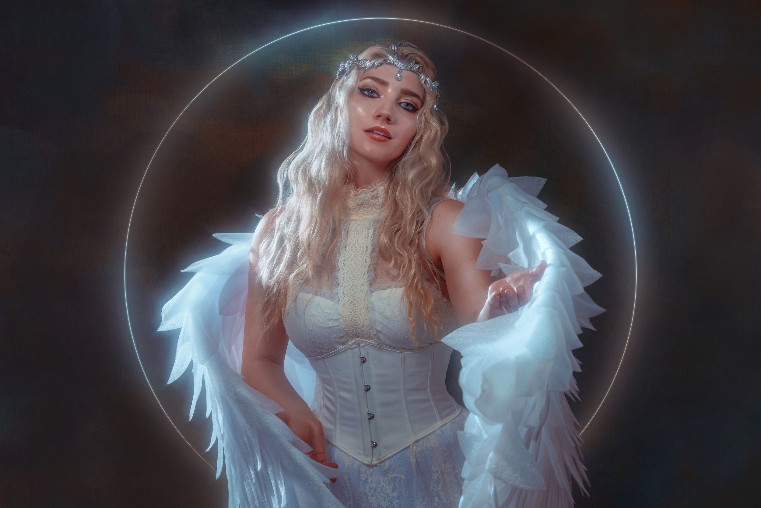 Woman in white corset dress with angel wings and halo, posing in ethereal fantasy portrait photography.