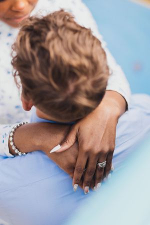 Close up view of hands resting on light blue medical examination table with gentle natural lighting.