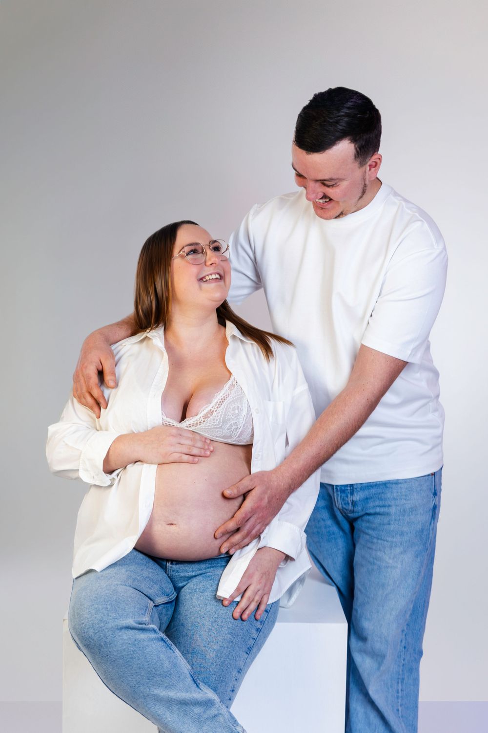 Séance photo minimaliste en studio d'une femme enceinte, capturant la douceur et la sérénité de la grossesse dans un cadre simple et épuré.