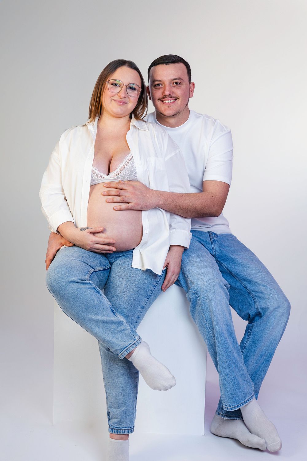 Séance photo minimaliste en studio d'une femme enceinte, capturant la douceur et la sérénité de la grossesse dans un cadre simple et épuré.