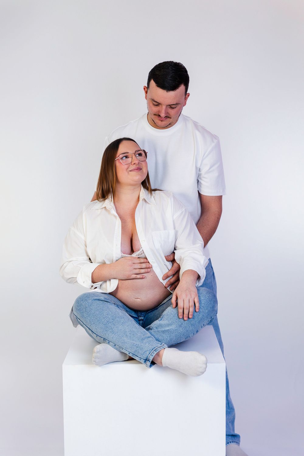 Séance photo minimaliste en studio d'une femme enceinte, capturant la douceur et la sérénité de la grossesse dans un cadre simple et épuré.