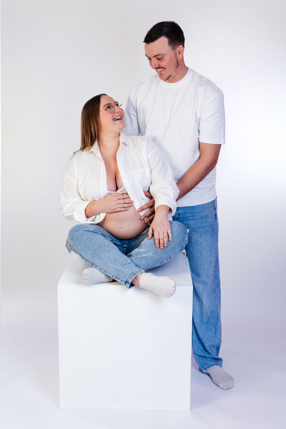 Séance photo minimaliste en studio d'une femme enceinte, capturant la douceur et la sérénité de la grossesse dans un cadre simple et épuré.