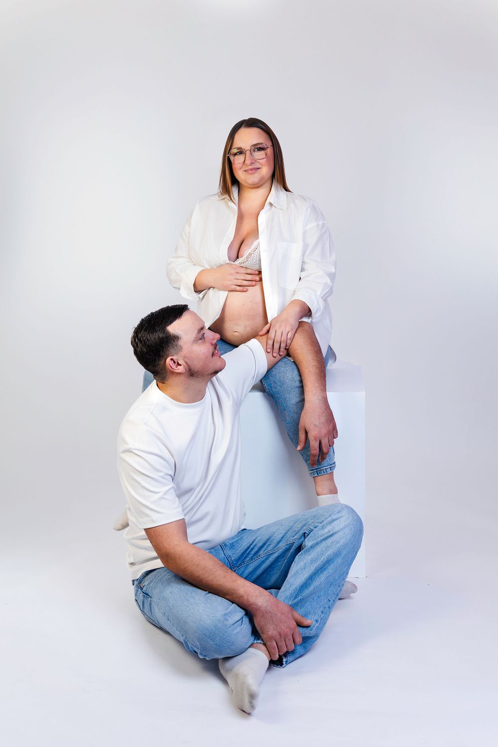 Séance photo minimaliste en studio d'une femme enceinte, capturant la douceur et la sérénité de la grossesse dans un cadre simple et épuré.
