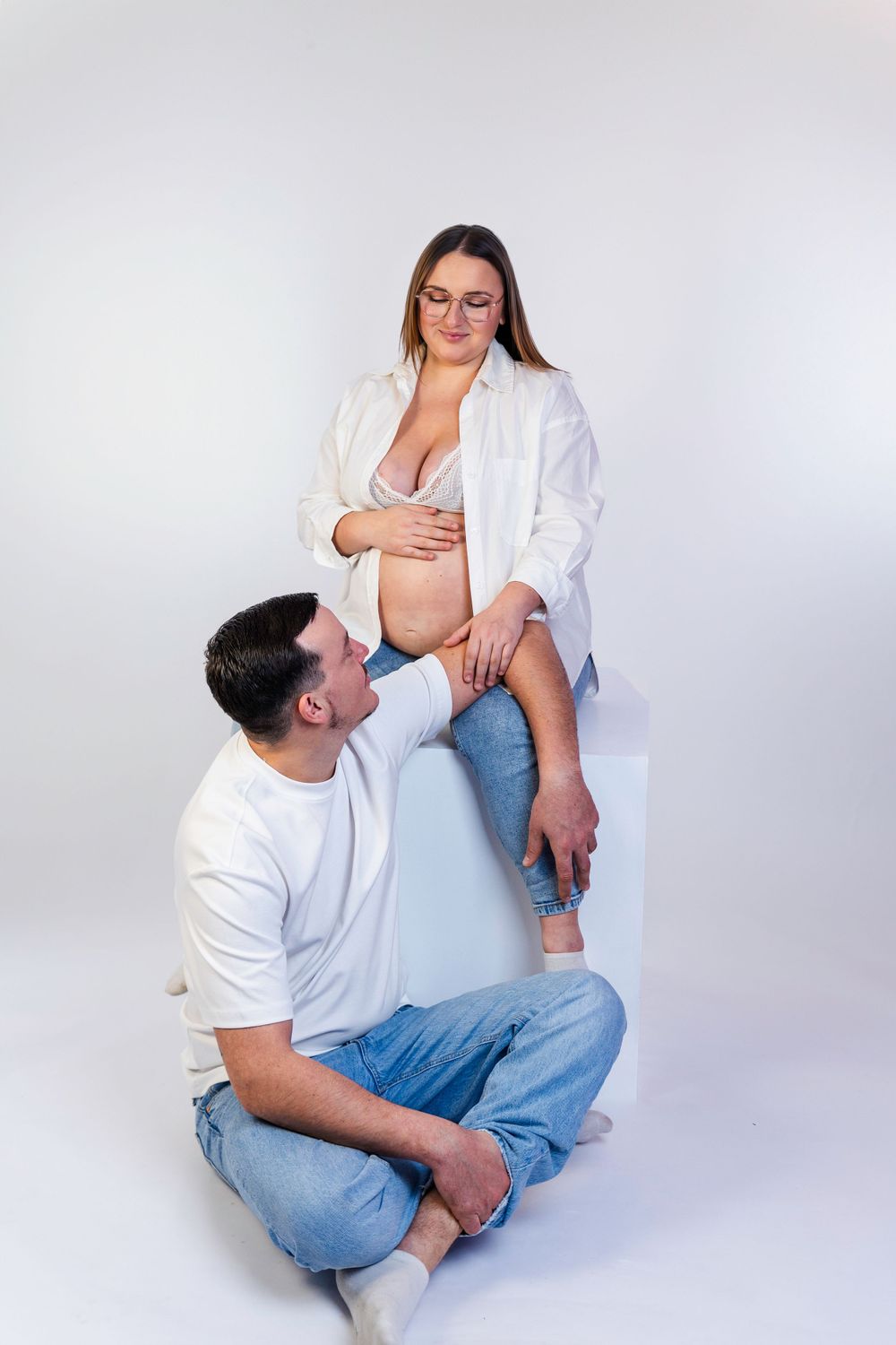 Séance photo minimaliste en studio d'une femme enceinte, capturant la douceur et la sérénité de la grossesse dans un cadre simple et épuré.