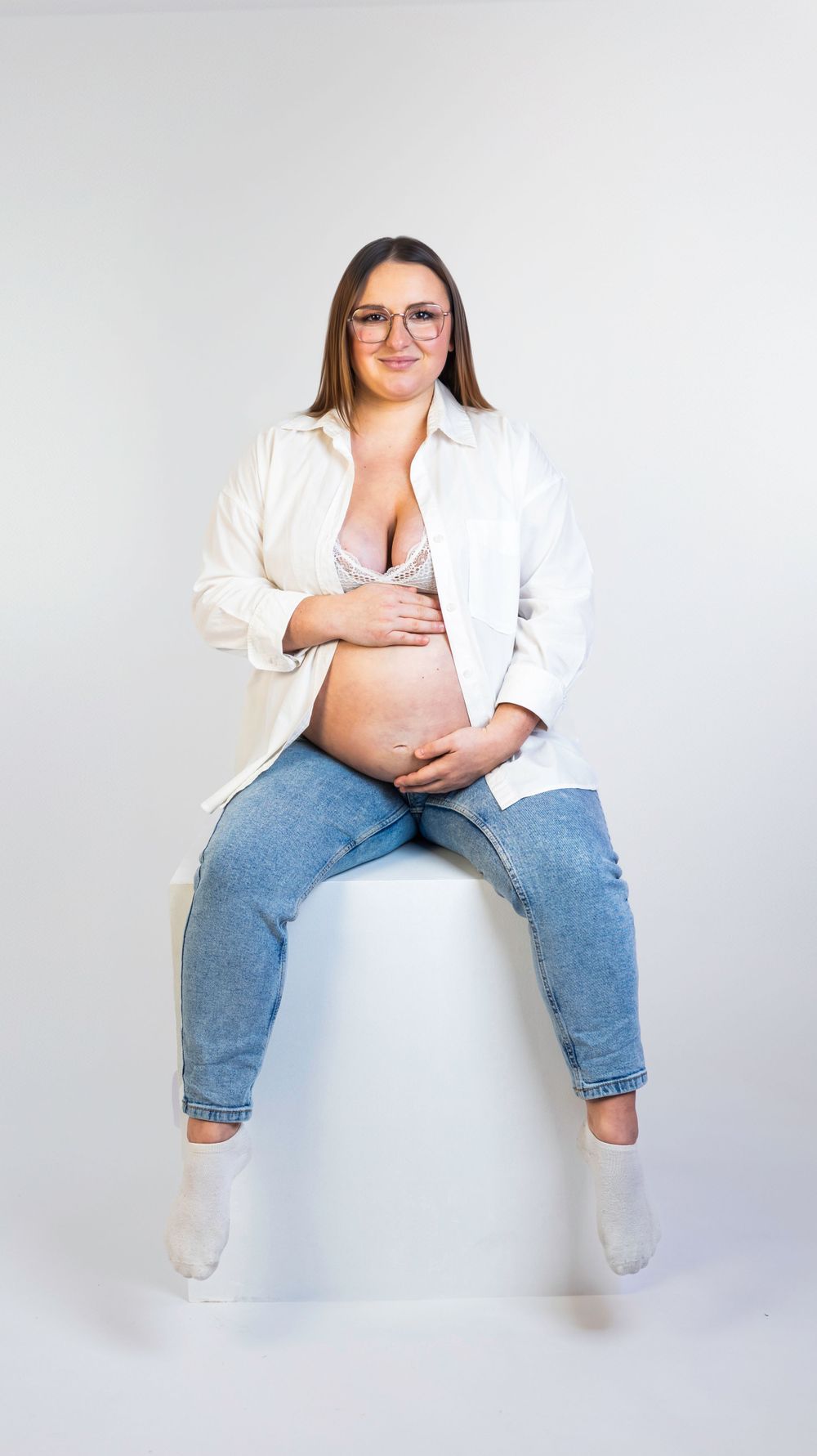Séance photo minimaliste en studio d'une femme enceinte, capturant la douceur et la sérénité de la grossesse dans un cadre simple et épuré.