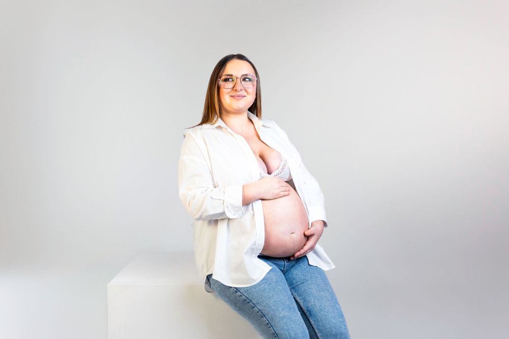 Séance photo minimaliste en studio d'une femme enceinte, capturant la douceur et la sérénité de la grossesse dans un cadre simple et épuré.