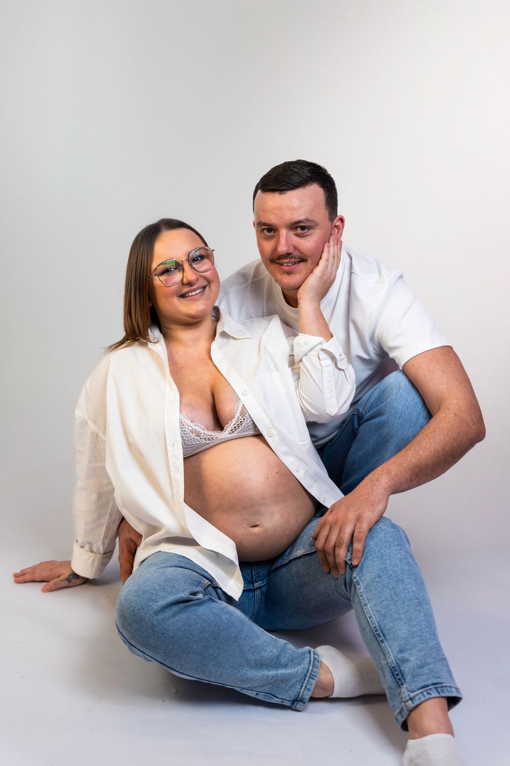 Séance photo minimaliste en studio d'une femme enceinte, capturant la douceur et la sérénité de la grossesse dans un cadre simple et épuré.