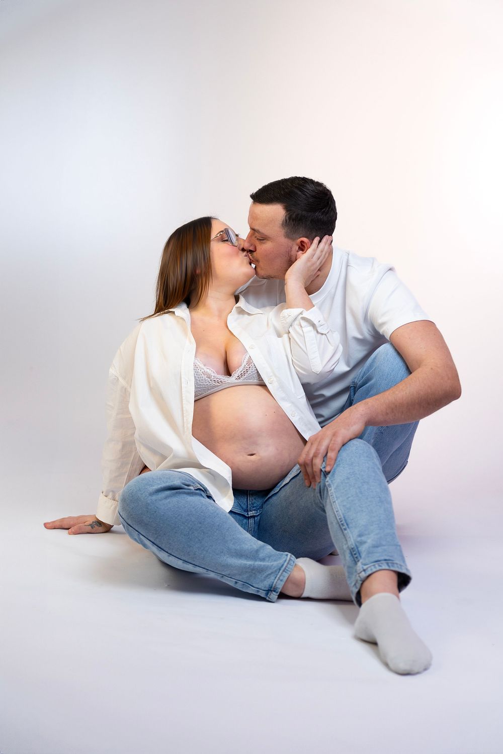 Séance photo minimaliste en studio d'une femme enceinte, capturant la douceur et la sérénité de la grossesse dans un cadre simple et épuré.