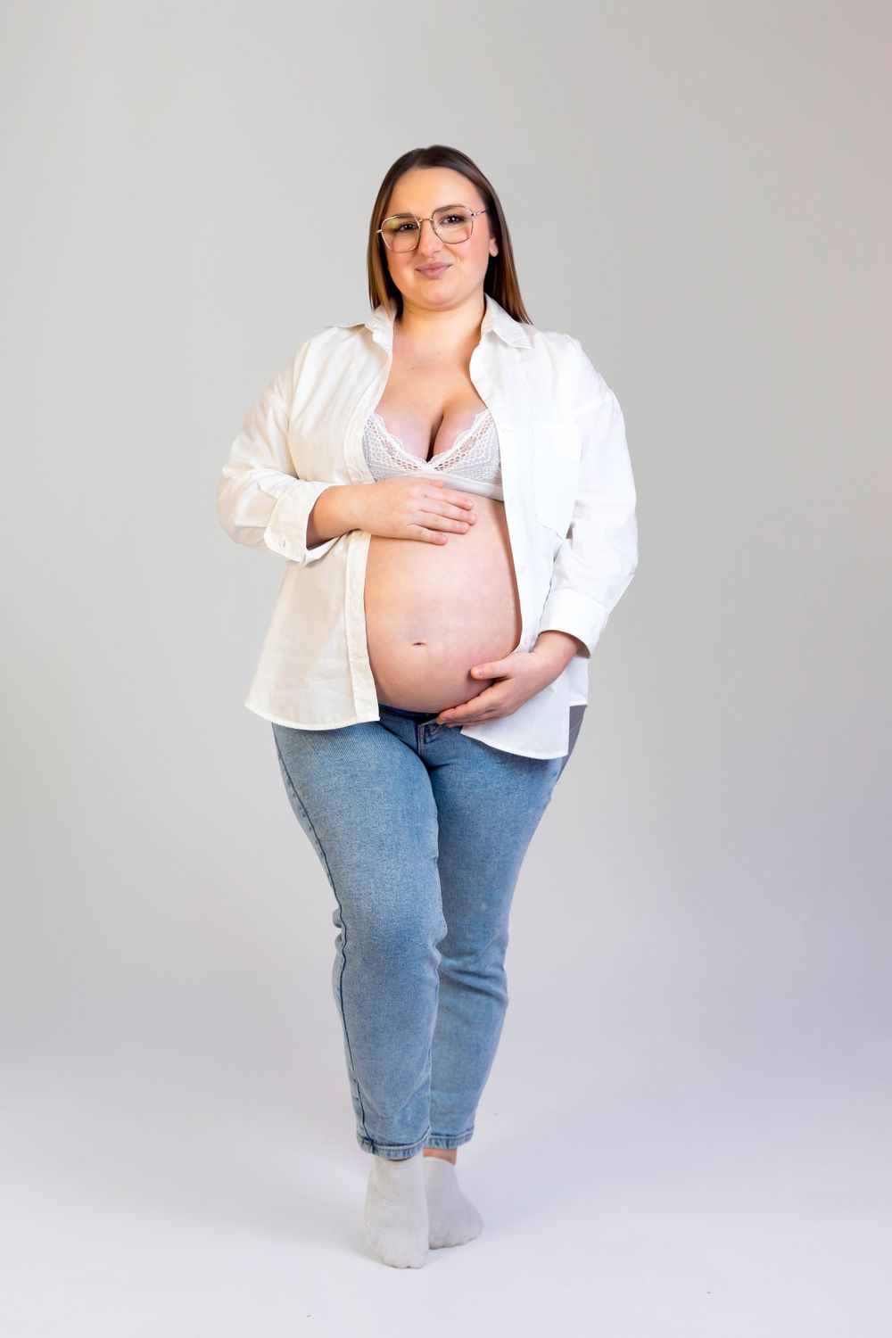 Séance photo minimaliste en studio d'une femme enceinte, capturant la douceur et la sérénité de la grossesse dans un cadre simple et épuré.