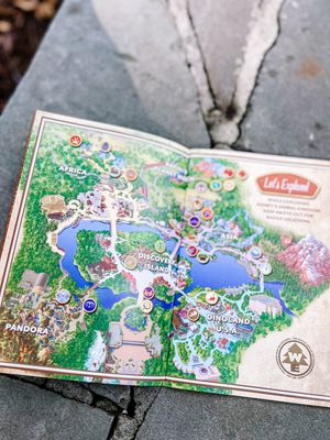 A detailed theme park map showing lakes, pathways and attractions laid out across different themed areas.