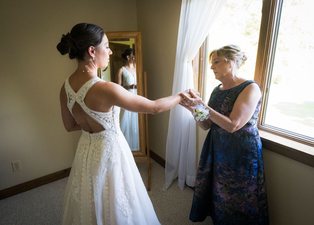 Two people prepare for a wedding ceremony in a sunlit getting-ready room.