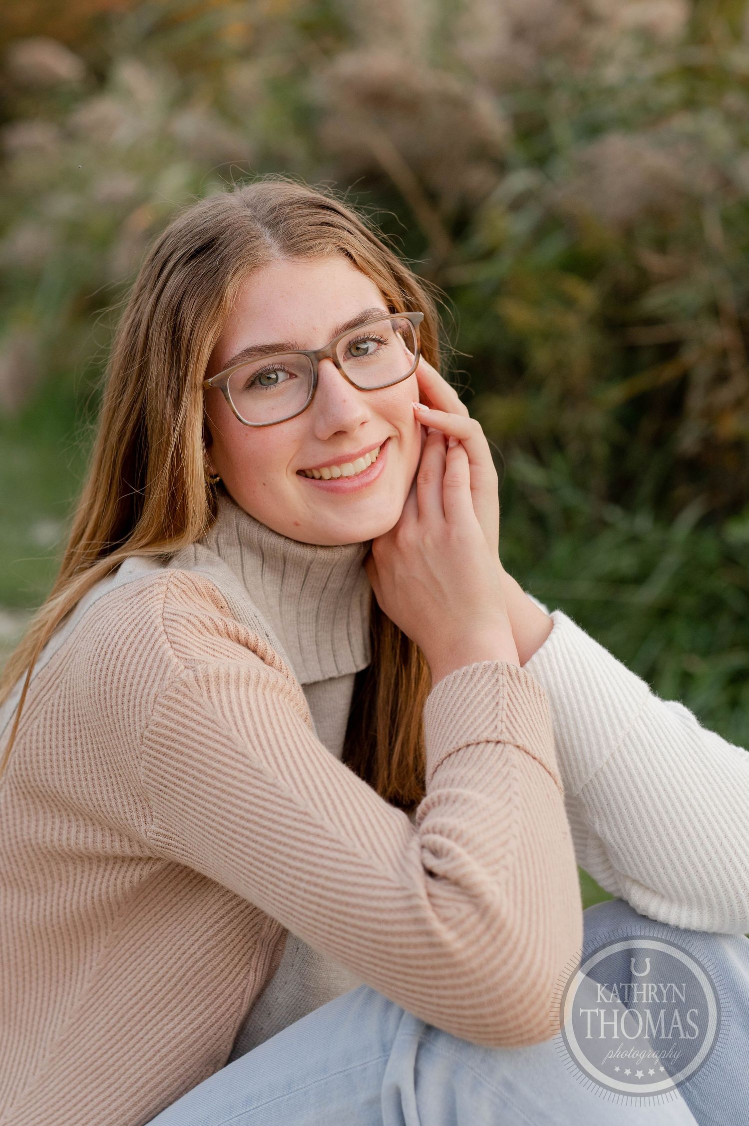 Close up portrait outdoors wearing beige turtleneck and glasses with natural background.