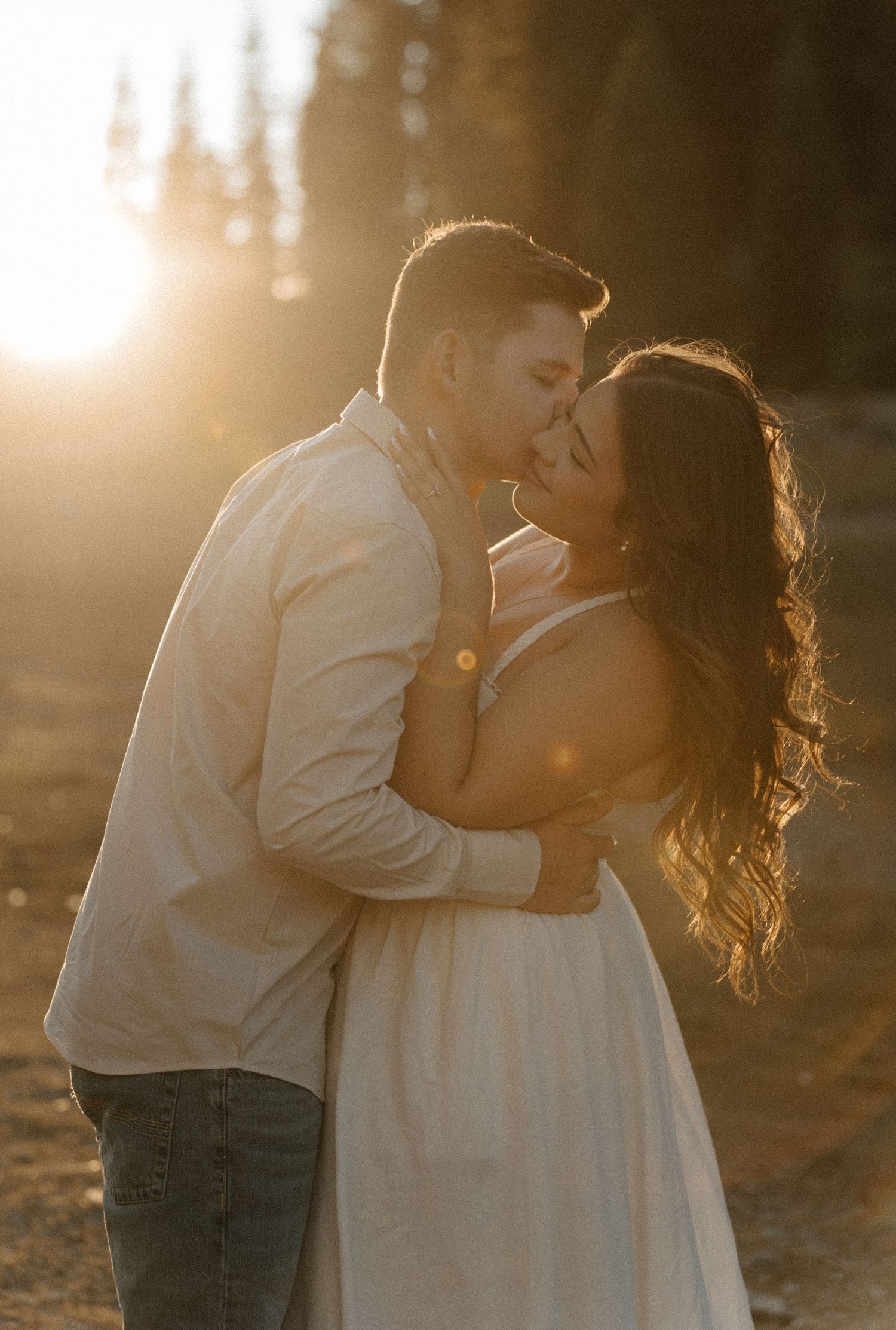 A bride and groom walk hand in hand along a garden path surrounded by lush greenery and warm golden sunlight.