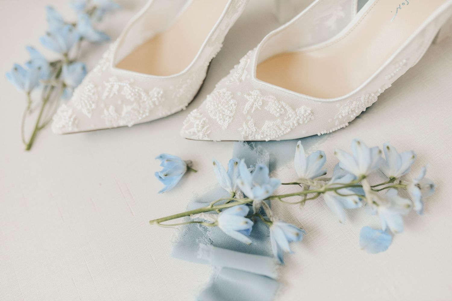 airy blue and ivory wedding detail styling with ribbon and floral accents