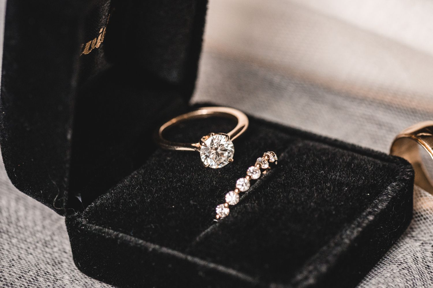 Rose gold diamond engagement ring and wedding band displayed in a black velvet jewelry box.
