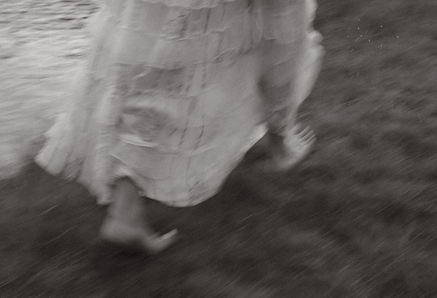 B&W artistic shot of a bride in a flowing white dress running through a grassy field in Central Oregon at Todd Lake, outside Bend, Oregon