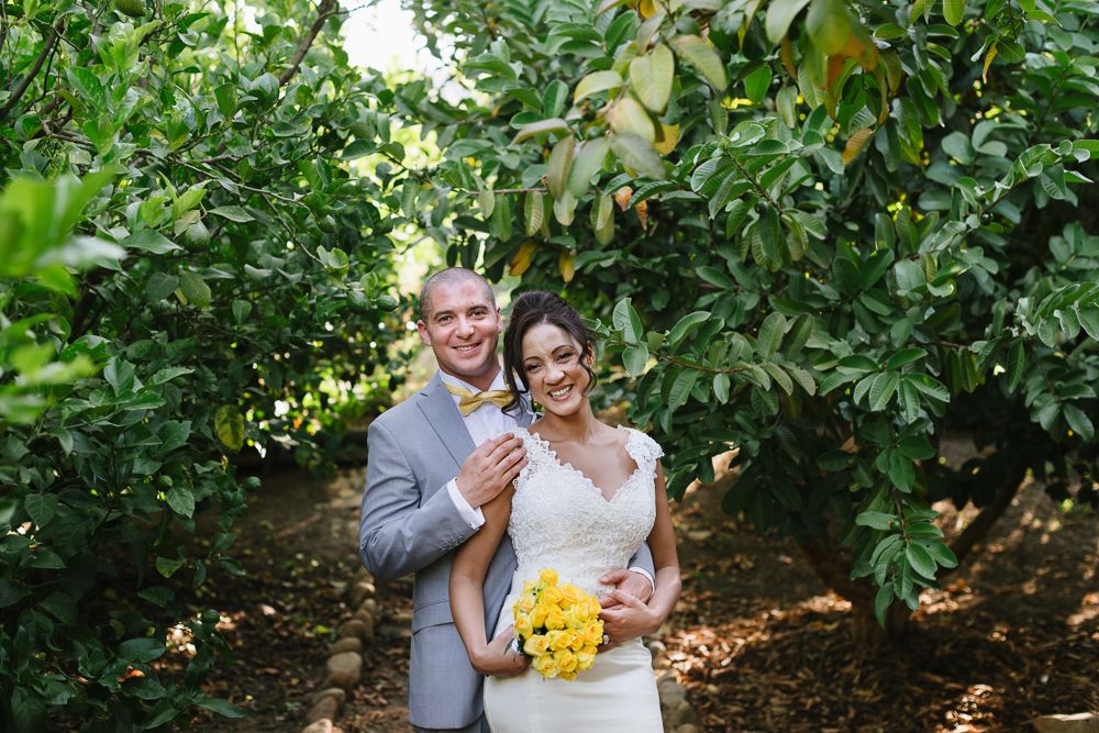 Bride and groom walk down the aisle after outdoor wedding ceremony surrounded by cheering guests in a lush garden setting.