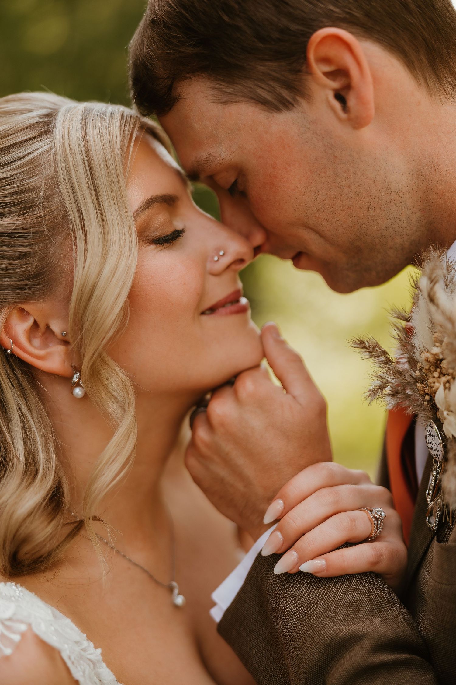 A bride and groom share an intimate moment, foreheads touching, as the groom gently cups her chin on their wedding day.