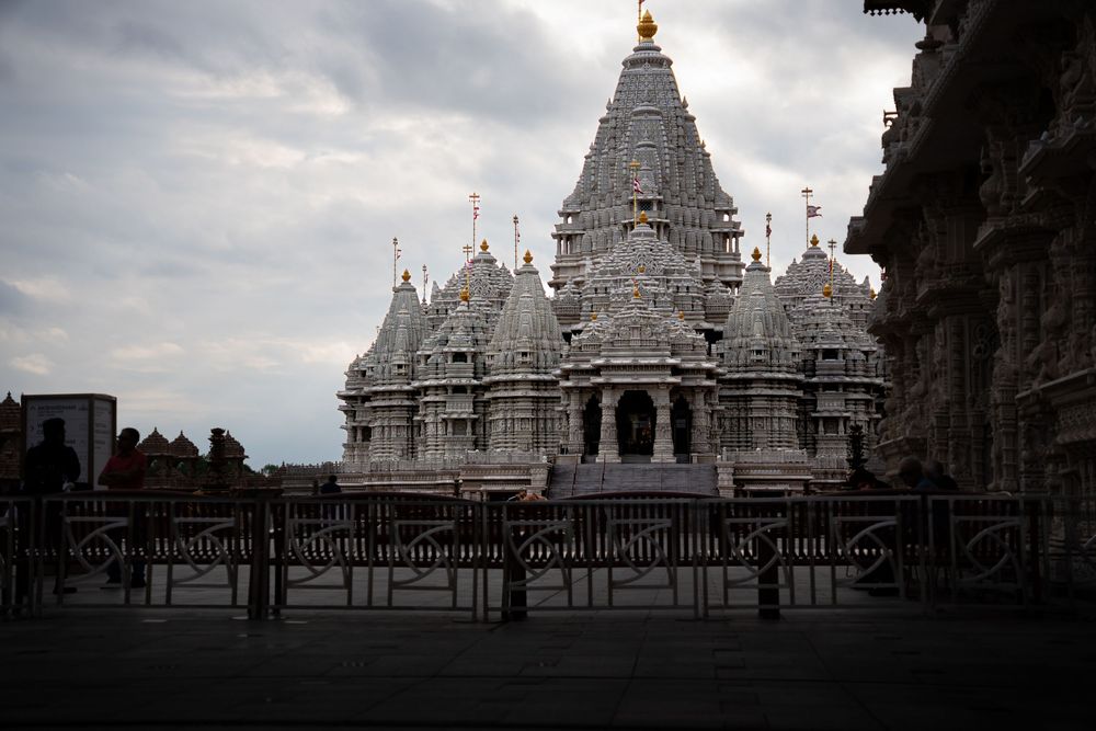 White marble Jain temple with ornate spires under a cloudy sky at dusk.