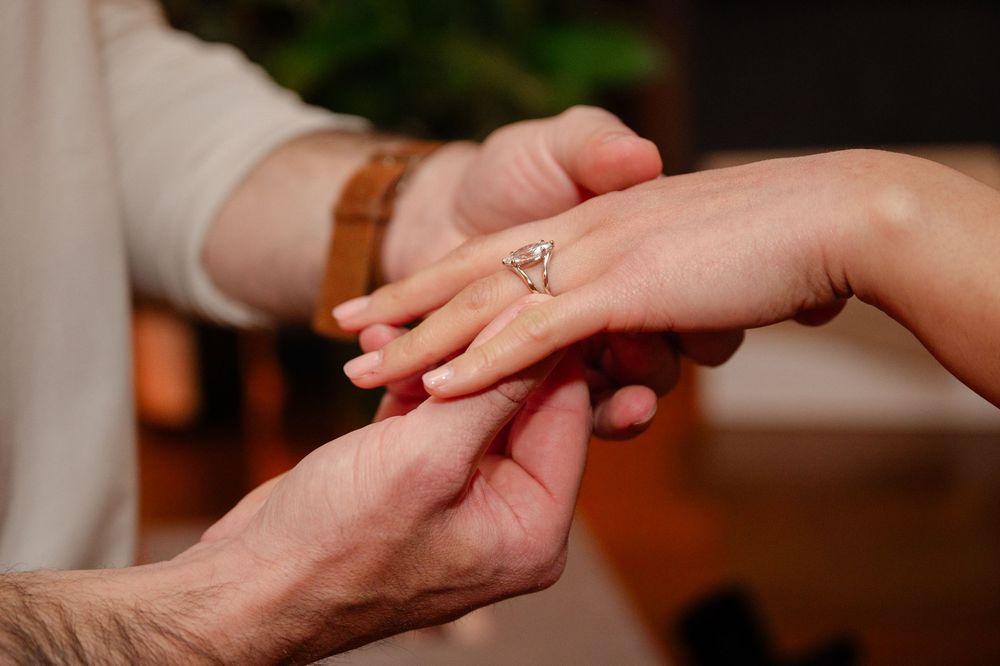 Close-up of an engagement ring being placed on a woman's finger during a proposal.