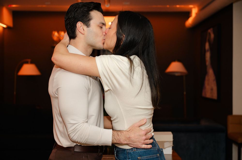 Happy couple sharing a passionate kiss during their engagement celebration indoors.
