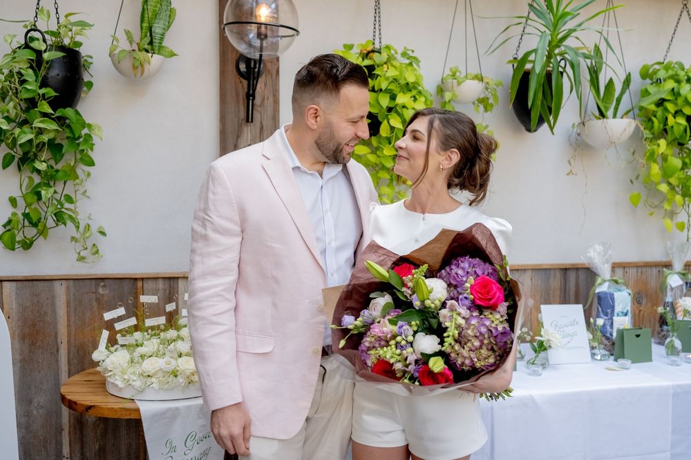 Couple sharing a romantic moment with colorful flower bouquet at elegant garden wedding reception.