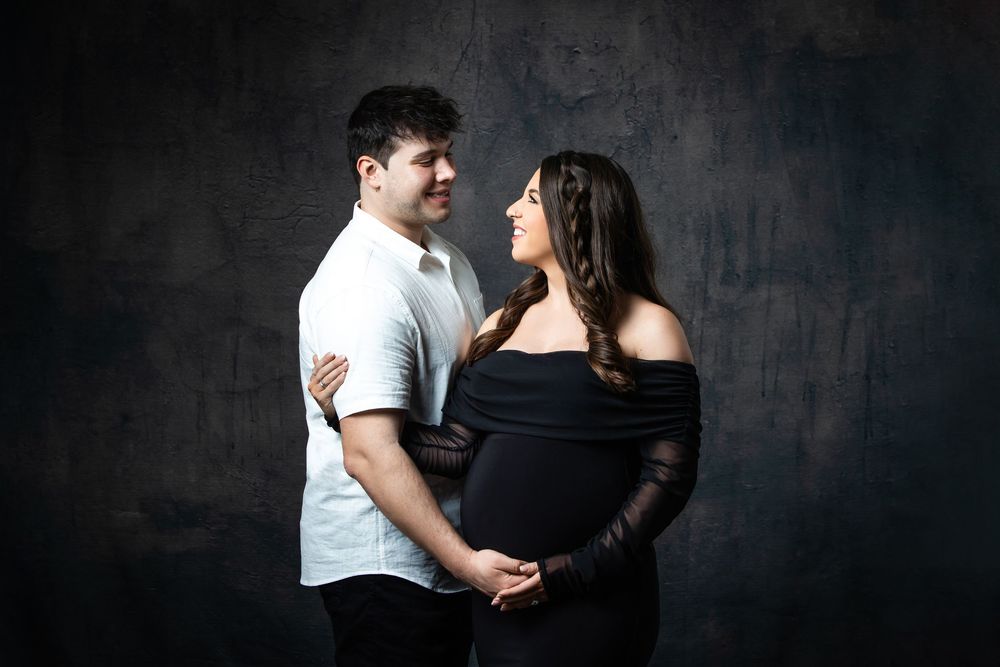 Expecting couple gazing at each other lovingly during professional maternity photo session.
