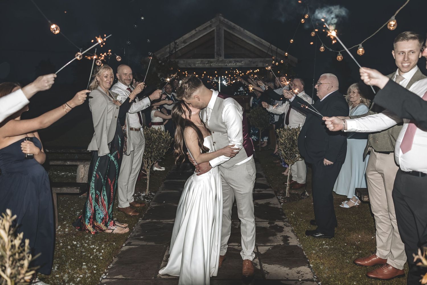 A celebrated sparkler exit celebrated by wedding guests as bride and groom share a moment.