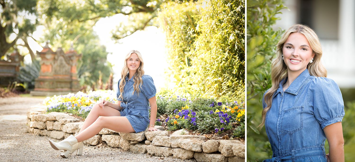 Young blonde woman in denim dress poses outdoors among colorful flowers and stone landscaping for senior portrait session.