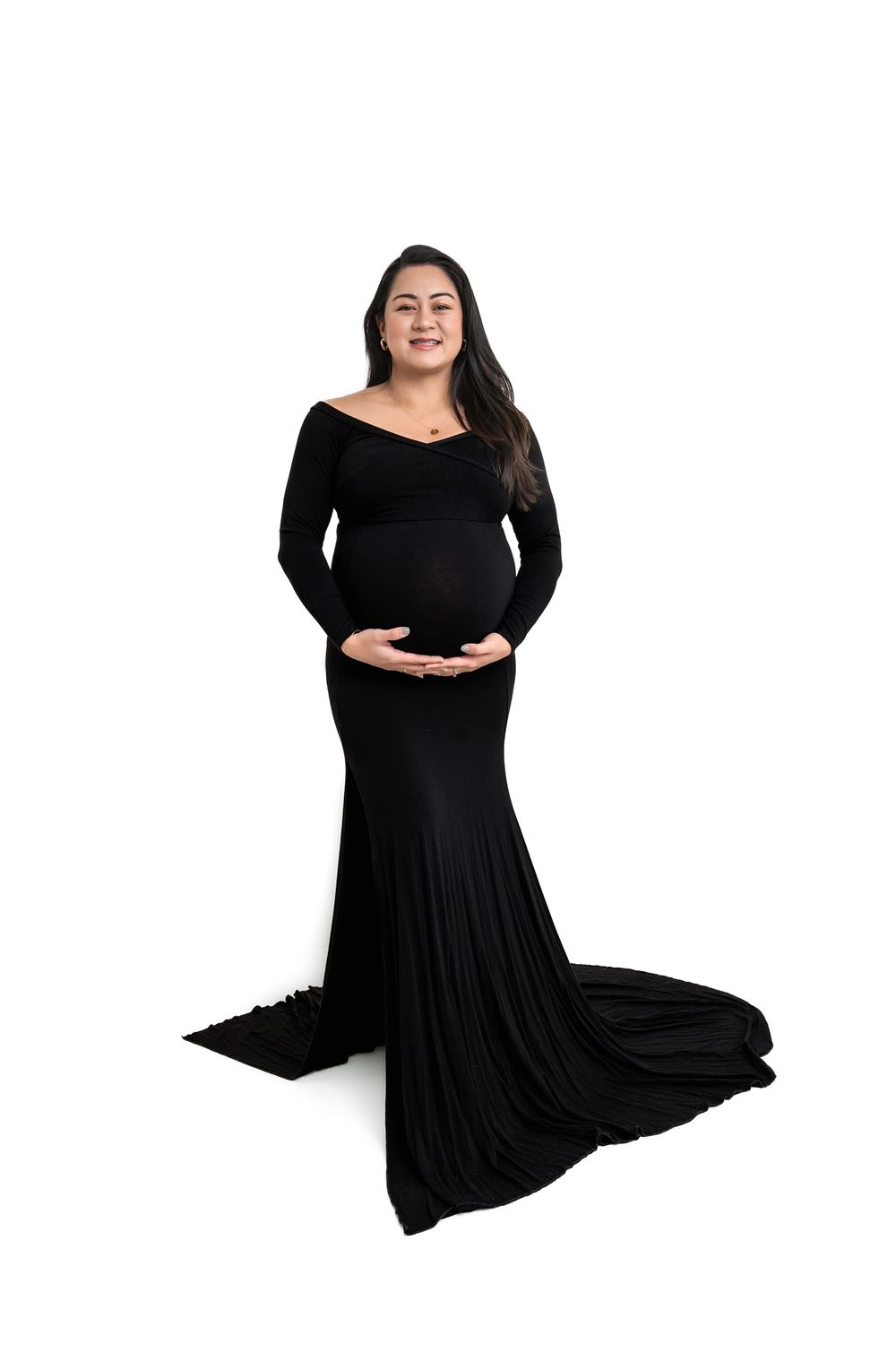 Pregnant woman in elegant black off-shoulder mermaid maternity gown posing in studio against white background.