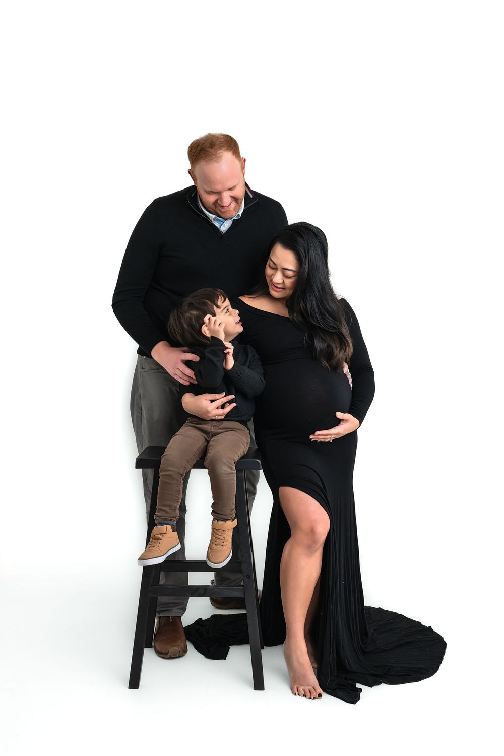 Maternity photo of a pregnant woman in a black gown with her partner and toddler son for studio maternity photos in Marietta.